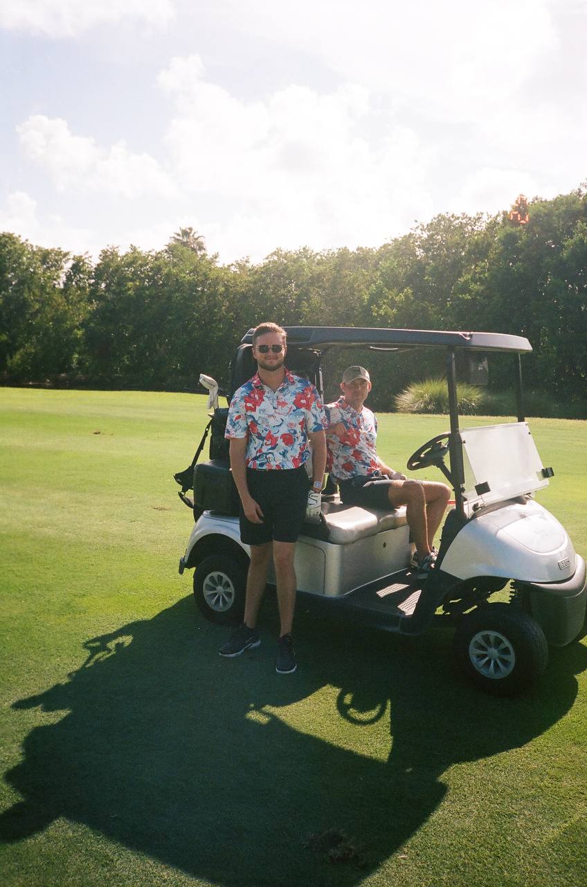Dawson Gant in a floral shirt at a golf cart with a friend