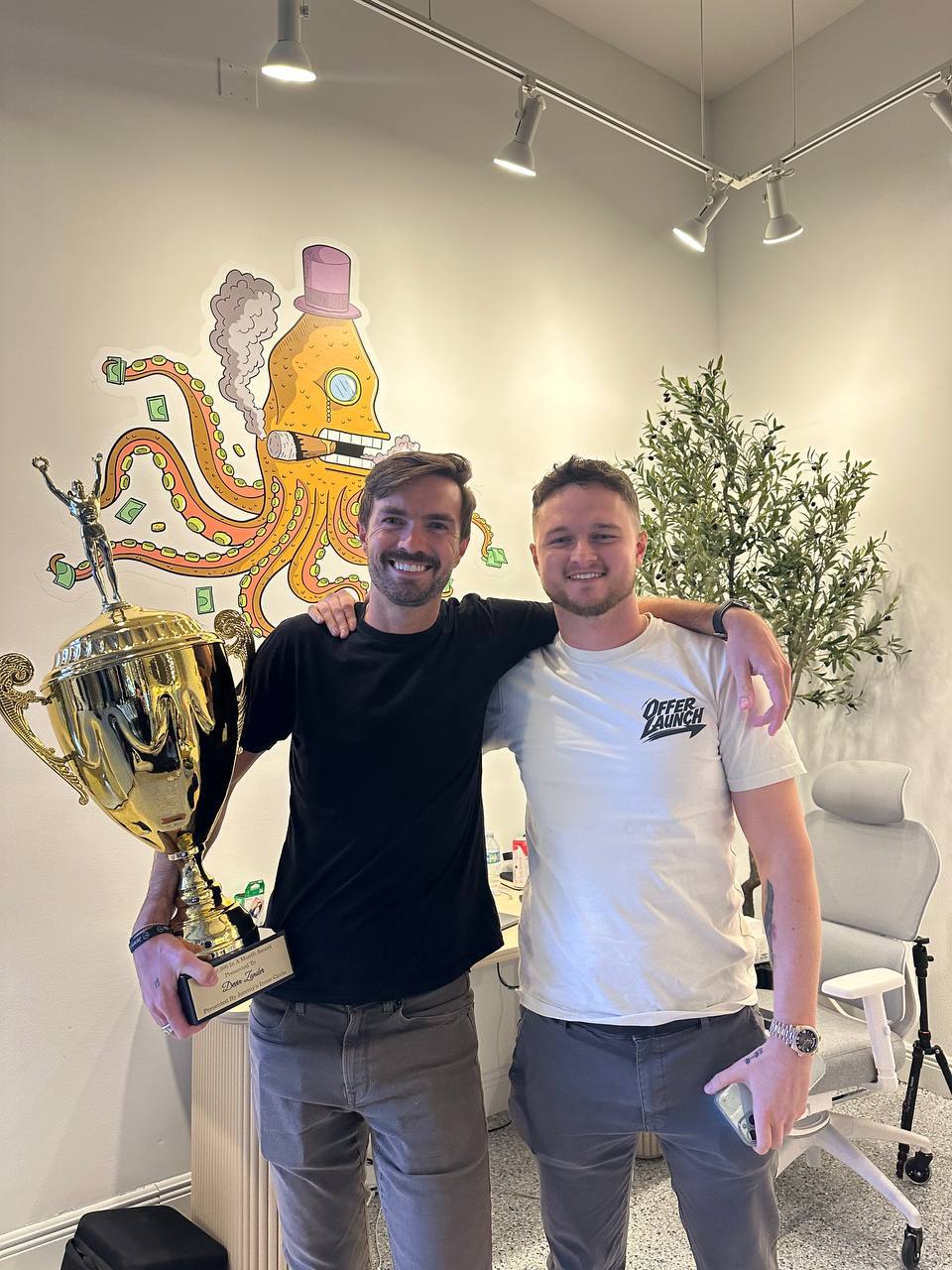 Dawson Gant with colleague holding a gold trophy at the OfferLaunch office